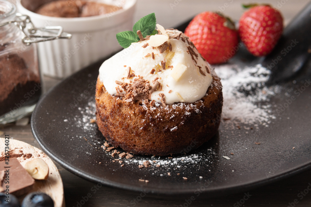 Cupcake with sweet cream and fruit on a wooden background