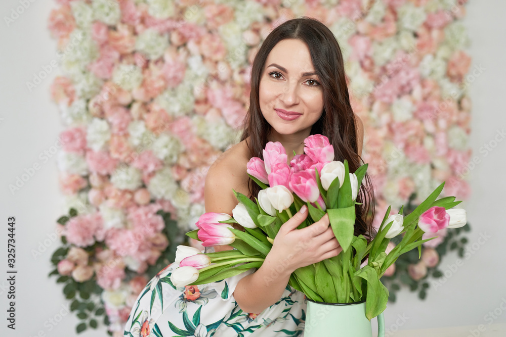 Beautiful girl with tulip flowers in hands on floral background. Greeting card for Women's Day March 8 or Mother's Day.Very nice florist woman holding beautiful colourful blossoming flowers bouquet Beautiful girl with tulip flowers in hands on floral background. Greeting card for Women's Day March 8 or Mother's Day.Very nice florist woman holding beautiful colourful blossoming flowers bouquet