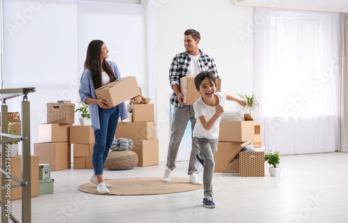 Happy family in room with cardboard boxes on moving day photo