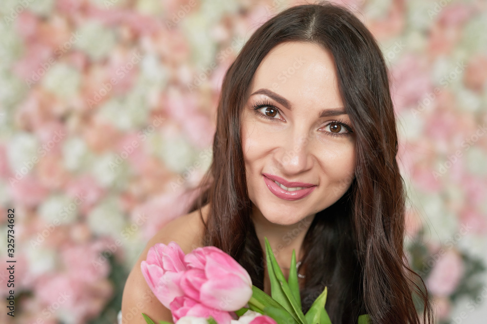 Beautiful girl with tulip flowers in hands on floral background. Greeting card for Women's Day March 8 or Mother's Day.Very nice florist woman holding beautiful colourful blossoming flowers bouquet Beautiful girl with tulip flowers in hands on floral background. Greeting card for Women's Day March 8 or Mother's Day.Very nice florist woman holding beautiful colourful blossoming flowers bouquet