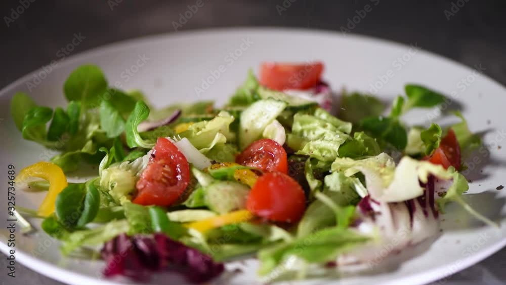 Preparation of vegetable salad with greens, cucumbers, tomatoes, pepper. Mixing green salad falling on stone plate. Top view. Vegan and raw food concept. Preparation of vegetable salad with greens, cucumbers, tomatoes, pepper. Mixing green salad falling on stone plate. Top view. Vegan and raw food concept.