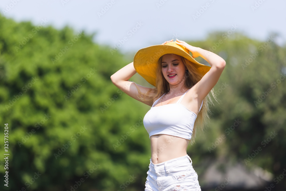 portrait beautiful young woman blonde hair smile with yellow hat posing outdoors in green garden.