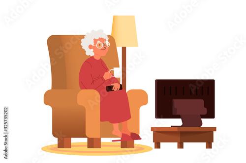 Old woman sitting in an armchair with a cup of tea and watching TV
