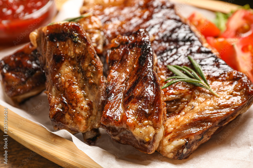 Delicious grilled ribs with rosemary on table, closeup Delicious grilled ribs with rosemary on table, closeup