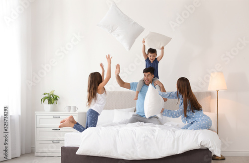 Happy family having pillow fight in bedroom Fototapet