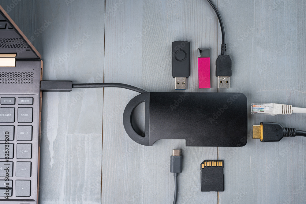 USB Type C adapter or hub connected to the laptop with various accessories - pendrives, hdmi, ethernet, memory card, cables. Flat lay top view.