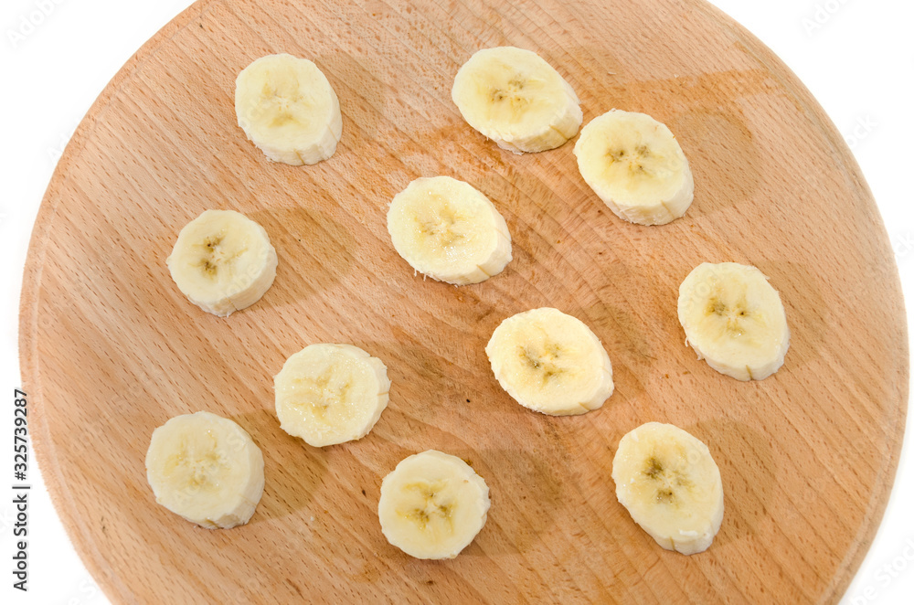sliced banana slices on a wooden board isolated on a white background. View from above. sliced banana slices on a wooden board isolated on a white background. View from above.