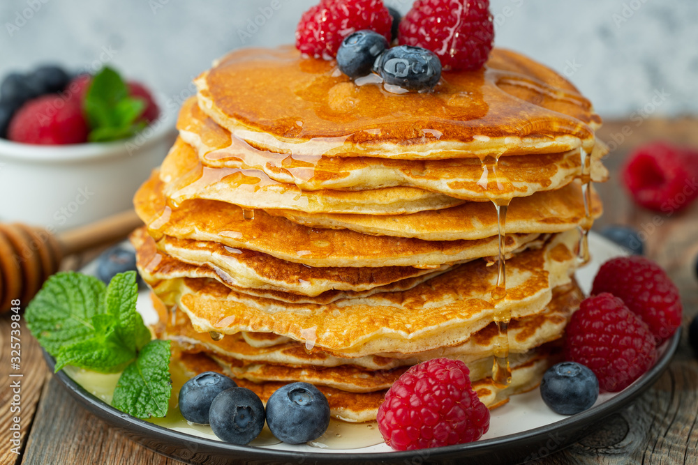 Close-up delicious pancakes, with fresh blueberries, raspberry's and honey on a light background Close-up delicious pancakes, with fresh blueberries, raspberry's and honey on a light background
