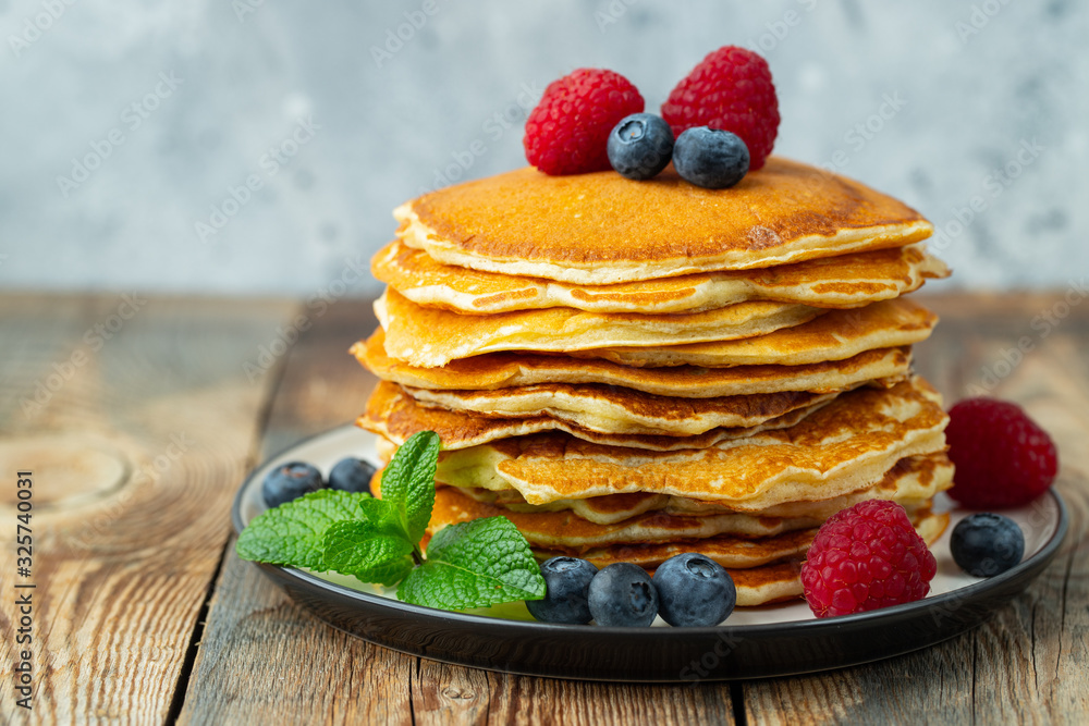 Close-up delicious pancakes, with fresh blueberries, raspberry's and honey on a light background Close-up delicious pancakes, with fresh blueberries, raspberry's and honey on a light background