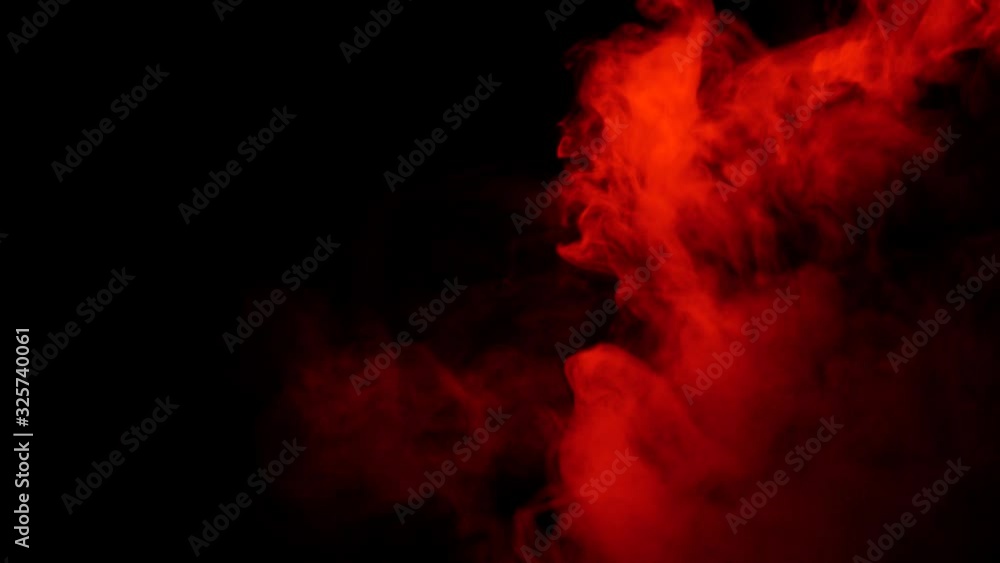 Red smoke on a black background. Color smoke slowly floating through space against black background. Red smoke on a black background. Color smoke slowly floating through space against black background.