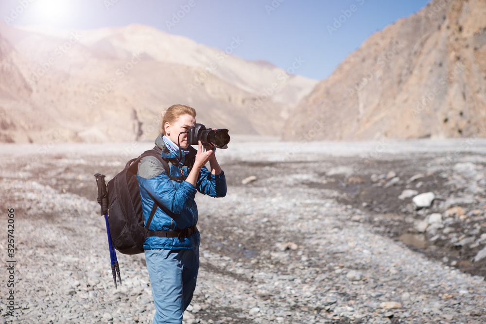 Beautiful woman photographer with backpack on a background of river valley and mountains. Nepal.