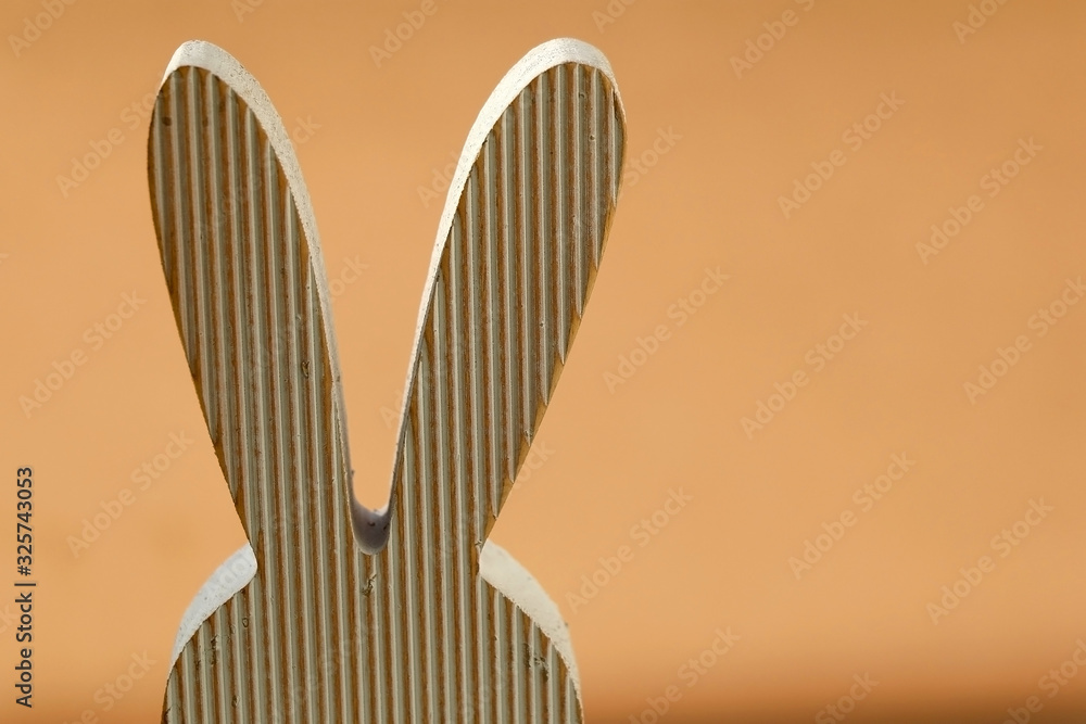 Wooden minimal Easter bunny decoration. Selective focus, pastel orange background. Wooden minimal Easter bunny decoration. Selective focus, pastel orange background.