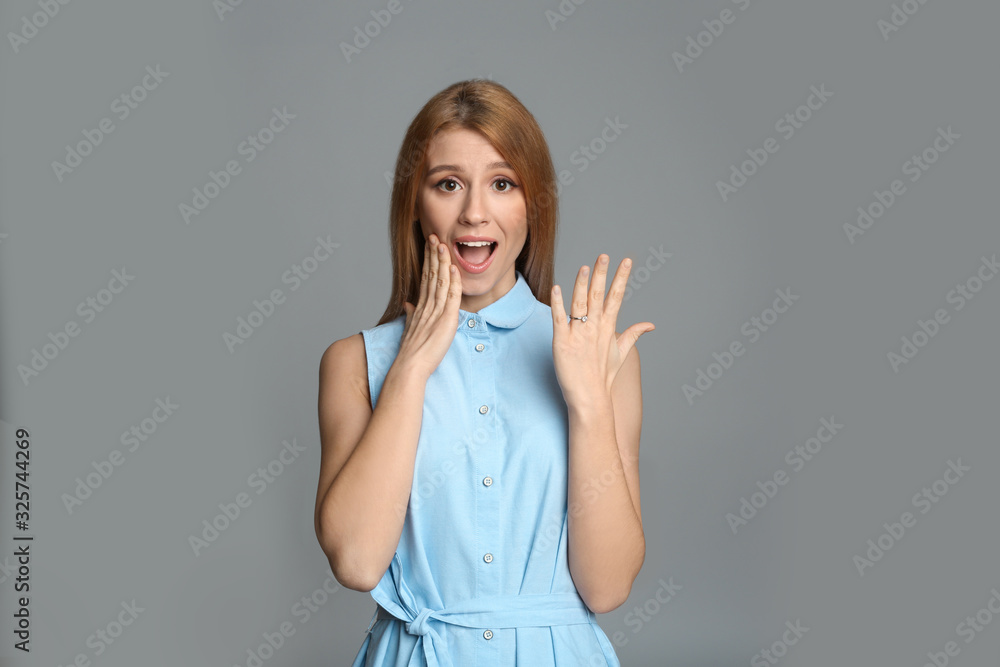 Excited woman with engagement ring on light grey background Excited woman with engagement ring on light grey background