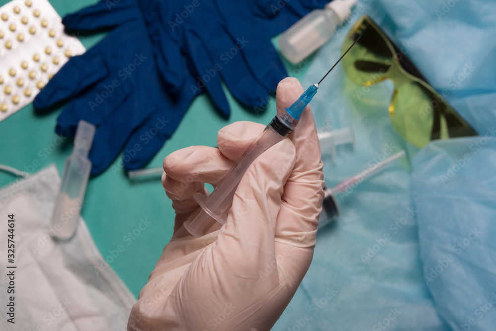 Doctor's hand holds a syringe. Hand with a syringe on a background of medical instruments. Doctor's hand holds a syringe. Hand with a syringe on a background of medical instruments.