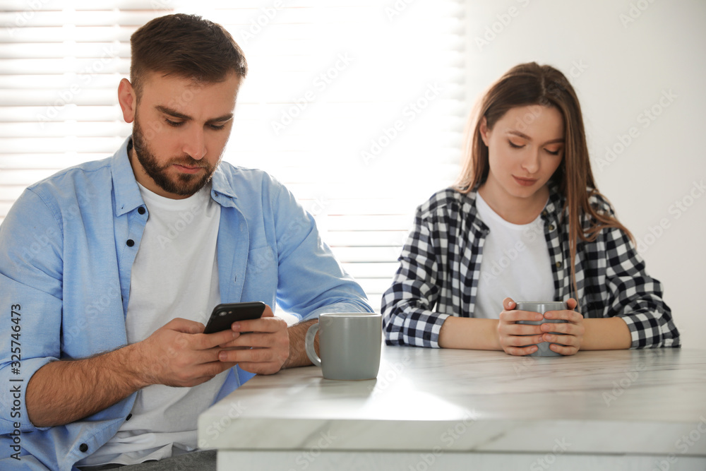 Young man preferring smartphone over his girlfriend at home. Relationship problems Young man preferring smartphone over his girlfriend at home. Relationship problems