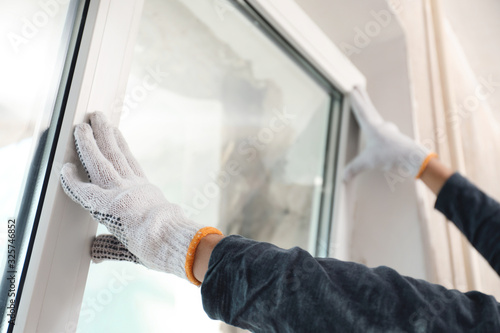 Worker installing plastic window indoors, closeup view photo