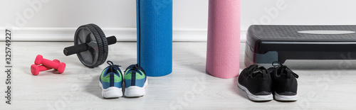 panoramic shot of yoga mats  sneakers  step platform and sport equipment on floor at home