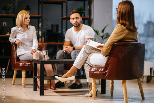 woman psychologist consulting young family consisted only of man and woman in modern office, couple can't get along with each other, troubles in relationships, so male and female visit psychologist