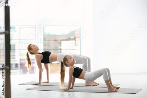 Mother and daughter in matching sportswear doing yoga together at home