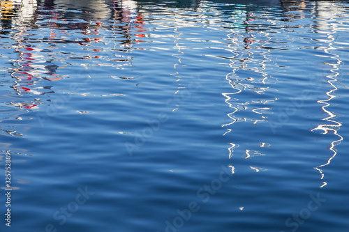 glare and reflection of masts of sailing boats and yachts on the sea surface