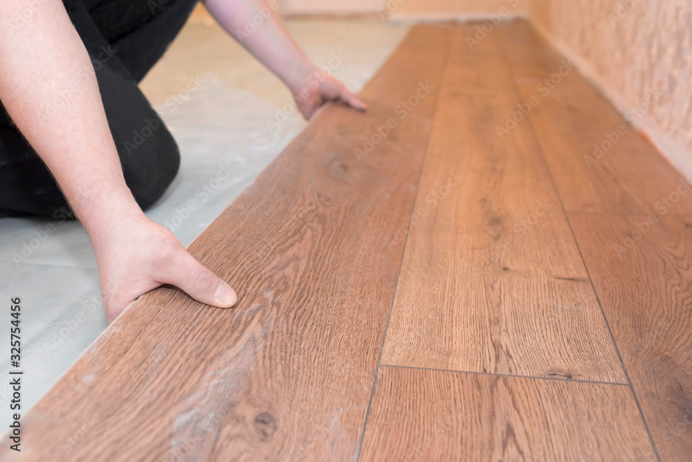 Worker installs a wooden parquet floor. Repair concept. Worker installs a wooden parquet floor. Repair concept.