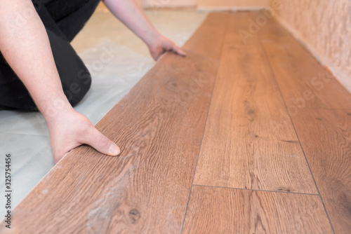 Worker installs a wooden parquet floor. Repair concept.