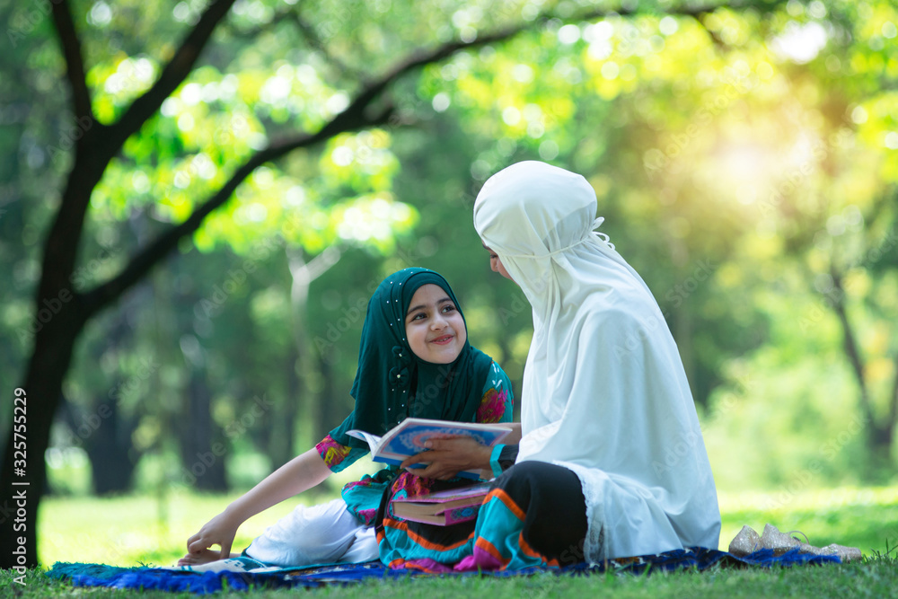 Muslim mother talking about Islam with adorable Muslim girl in hijab at