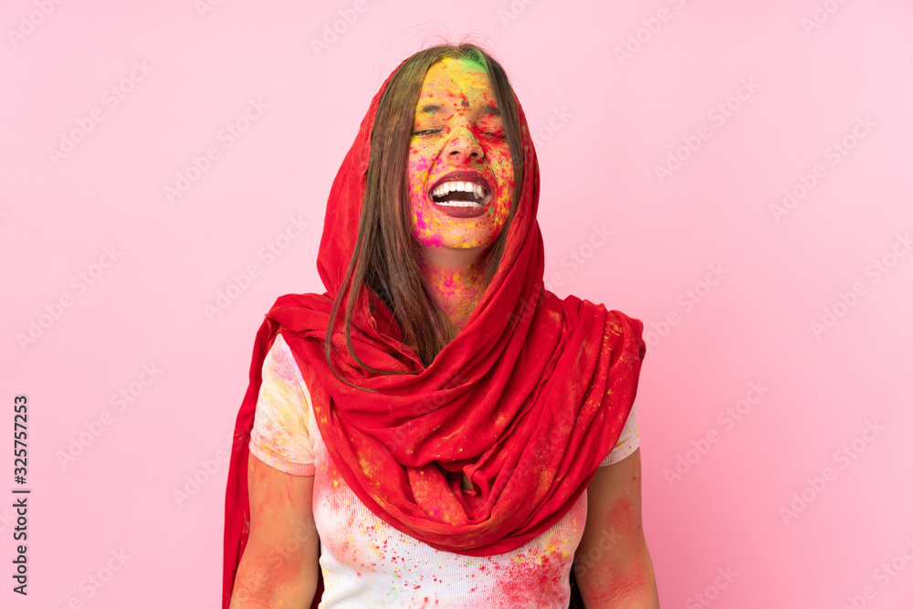 Young Indian woman with colorful holi powders on her face isolated on pink background laughing Young Indian woman with colorful holi powders on her face isolated on pink background laughing