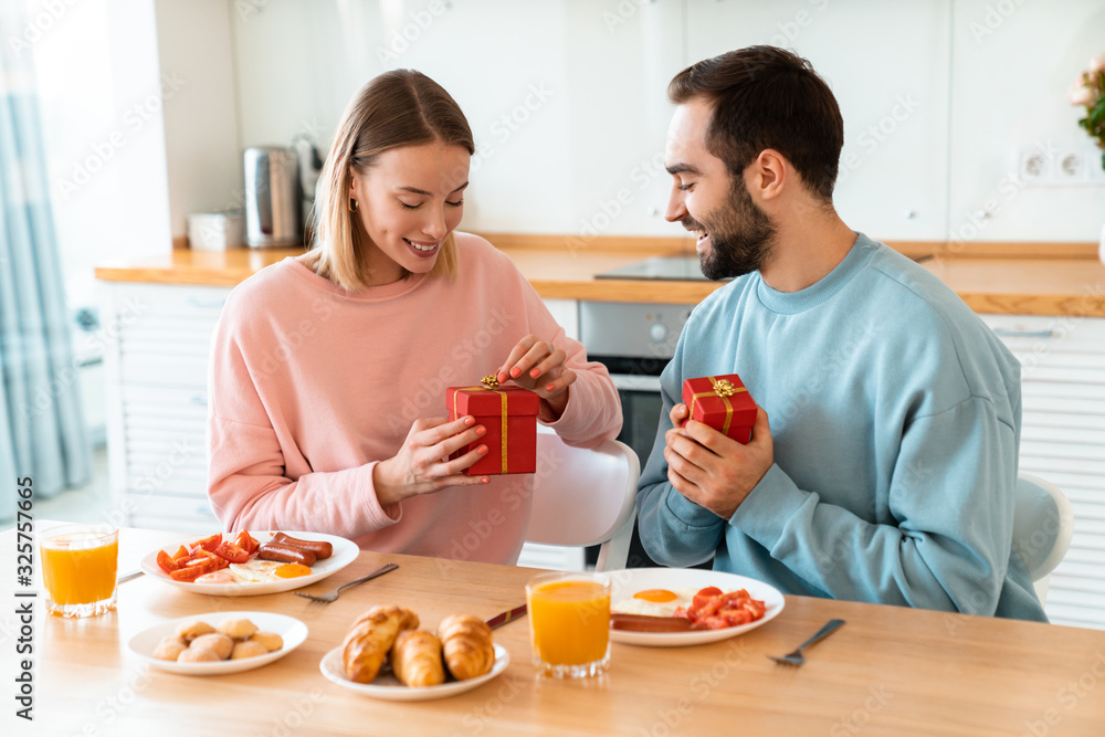 Portrait of happy couple holding gift boxes while having breakfast