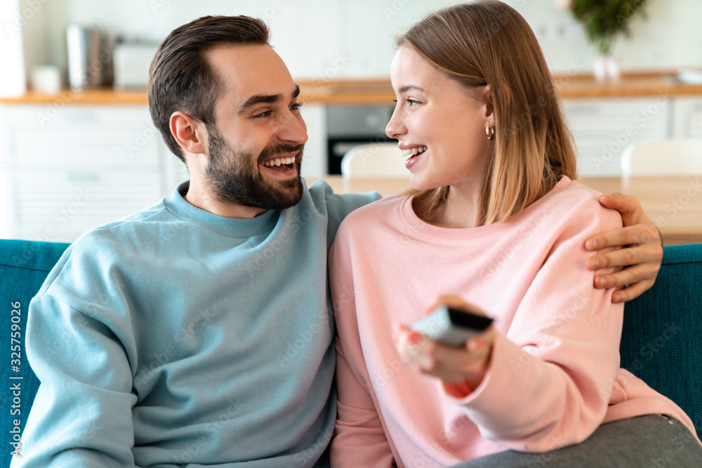 Portrait of young joyful couple hugging and watching TV Portrait of young joyful couple hugging and watching TV