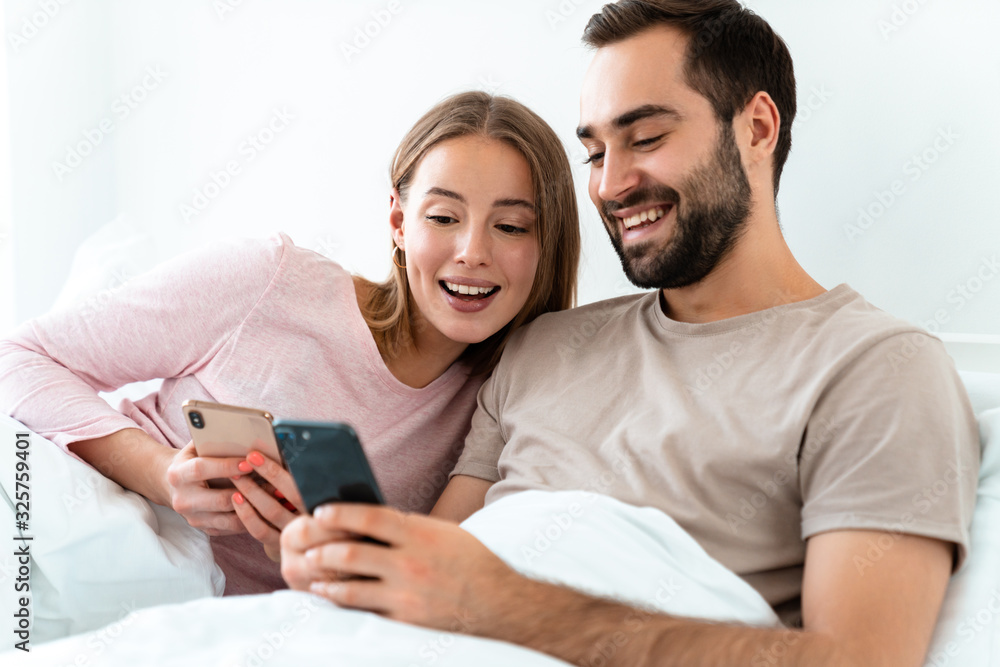 Portrait of beautiful joyful couple smiling and using smartphones Portrait of beautiful joyful couple smiling and using smartphones