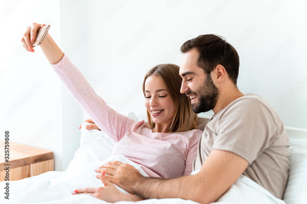 Portrait of joyful couple hugging and taking selfie photo on smartphone Portrait of joyful couple hugging and taking selfie photo on smartphone