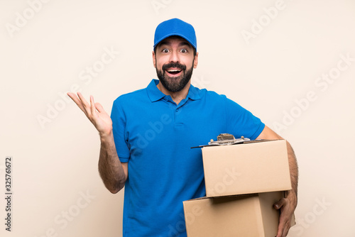 Delivery man with beard over isolated background with shocked facial expression