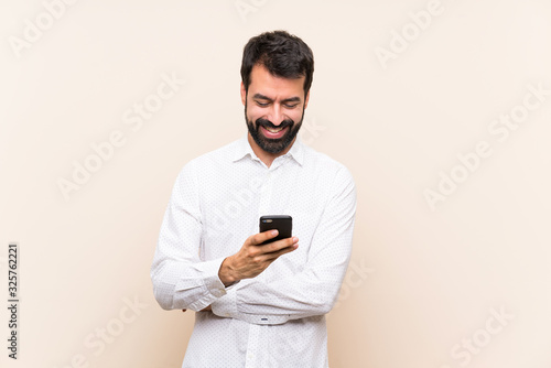 Young man with beard holding a mobile sending a message with the mobile