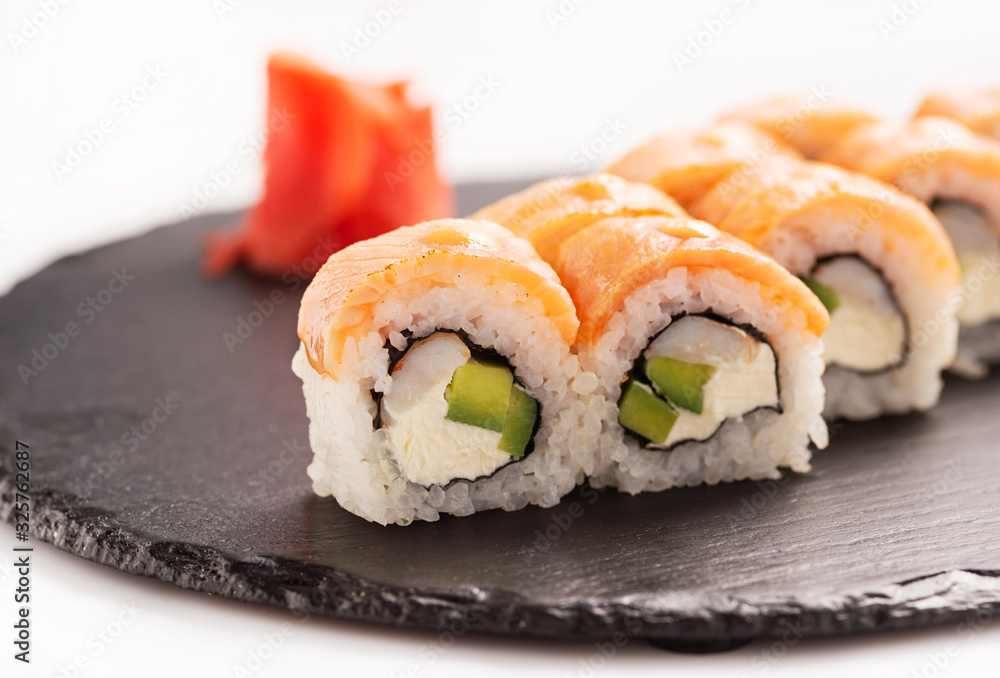 Sushi roll Philadelphia on the black round stone. Close up.