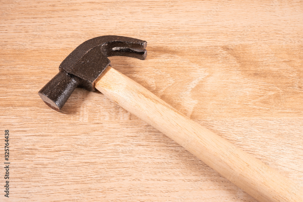 Hammer on wooden table .