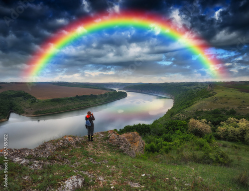 rainbow over the river. tourist on the rock. spring landscape