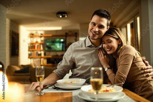 Young couple in love sitting embraced at dining table.