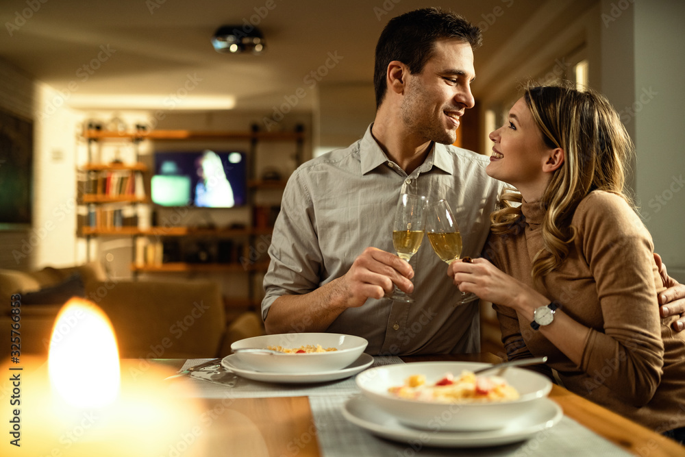 Embraced couple looking at each other while toasting with Champagne at dining table. Embraced couple looking at each other while toasting with Champagne at dining table.