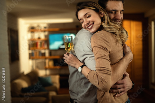 Happy woman with eyes closed embracing with her boyfriend at home.