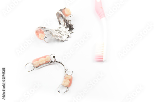 removable partial denture with tooth brush on white background.