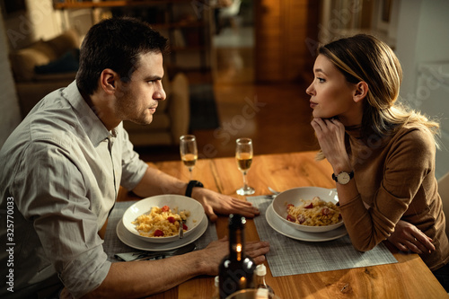 Young couple displeased couple talking to each other at dining table.