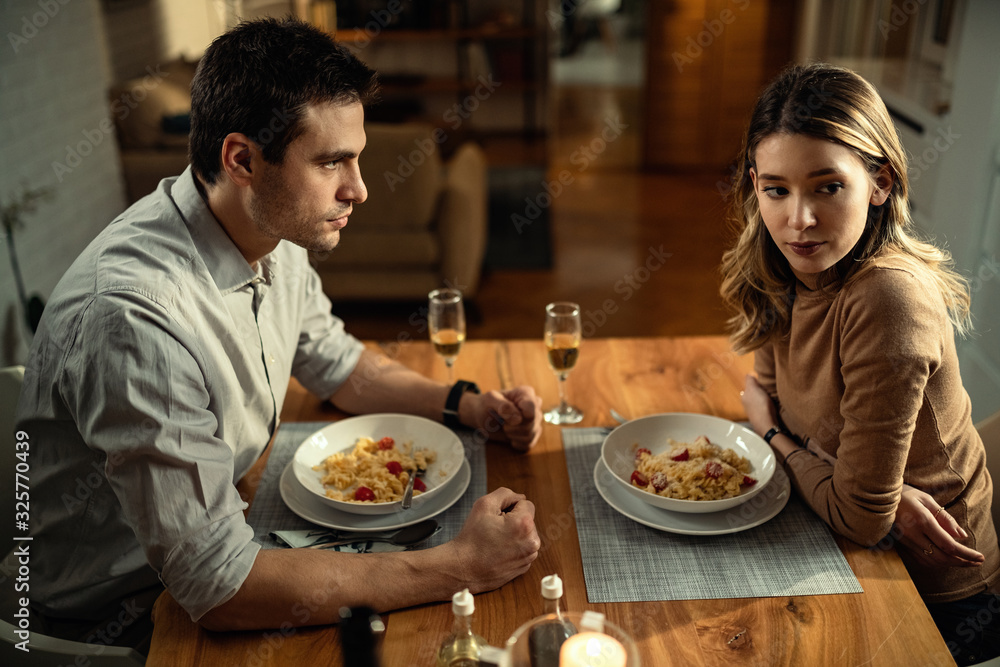 Distraught couple having an argument at dining table.