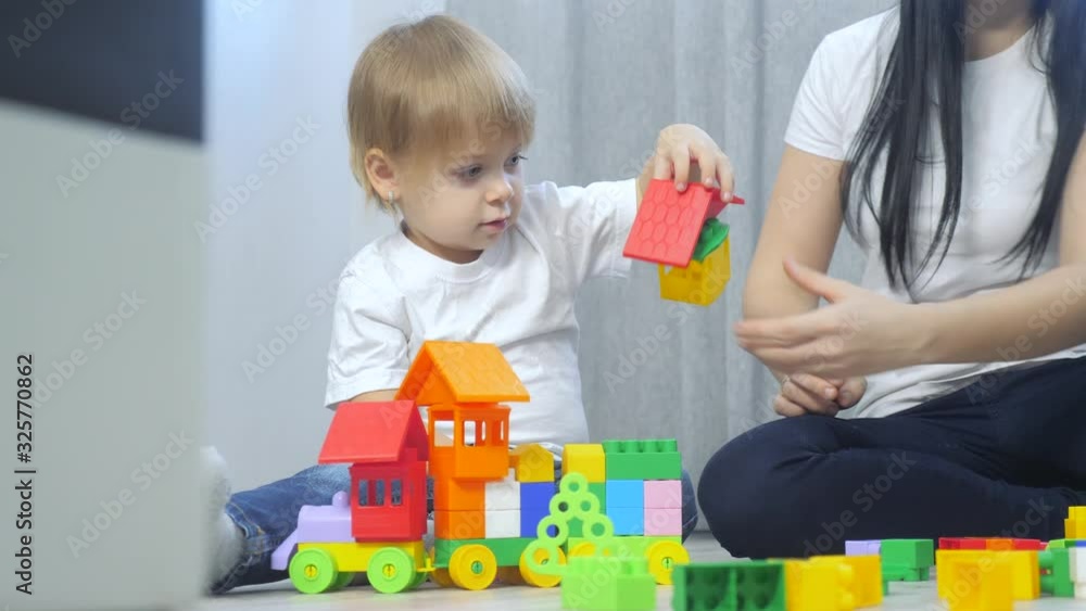 childhood happy family mom and children are playing concept little girl and boy brother and sister collects constructor teamwork. child plays toys sitting on floor. children play in team toys on childhood happy family mom and children are playing concept little girl and boy brother and sister collects constructor teamwork. child plays toys sitting on floor. children play in team toys on