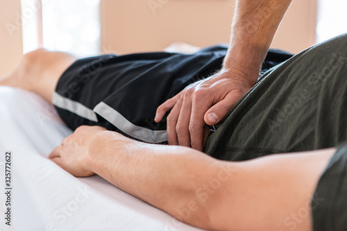 An unrecognizable physiotherapist masseur working. Strong muscular sportsman receiving healthy massage on the table. Body massage therapy photo