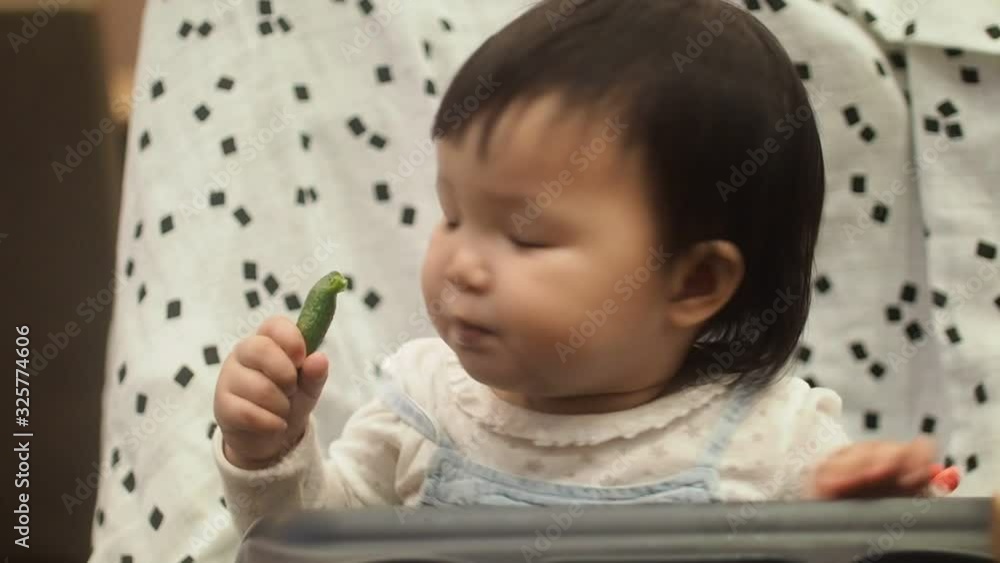 Cute asian infant baby girl is eatting finger food and looking for her parent.Close up, Cute asian infant baby girl is eatting finger food and looking for her parent.Close up,
