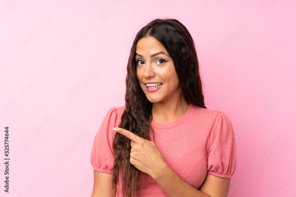 Young woman over isolated pink background pointing finger to the side Young woman over isolated pink background pointing finger to the side