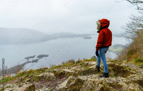 A female hiker in a red jacket standing on top on Surprise viewpoint in Lake District, United Kingdom