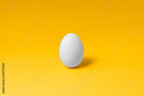 one white egg in center on yellow background. easter concept design