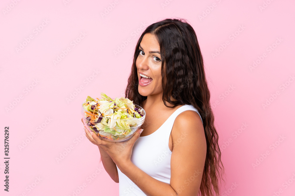 Young woman with salad over isolated wall